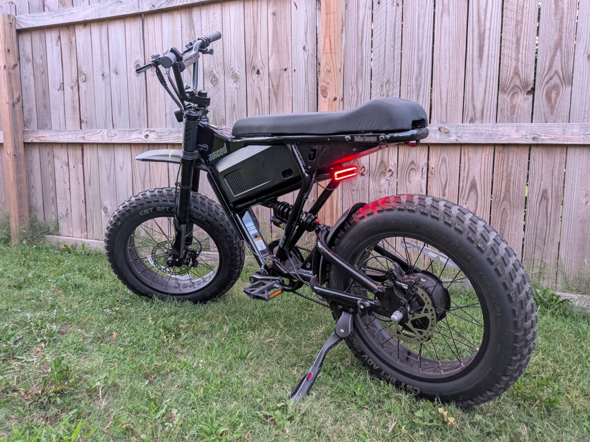 Rear three-quarter view with the taillight lit on the Juiced Scrambler Full Suspension