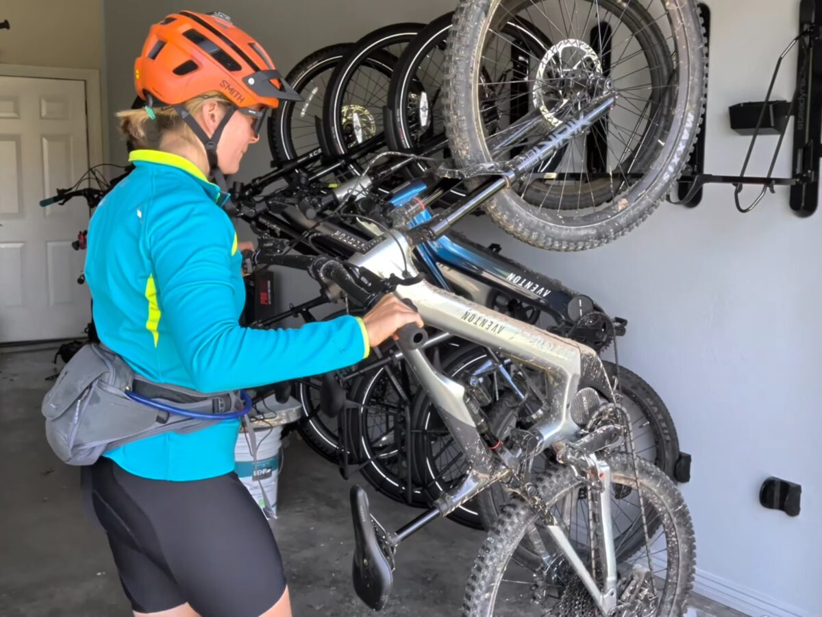 Rider in a helmet loading a muddy Aventon electric mountain bike onto a Steadyrack ProFlex